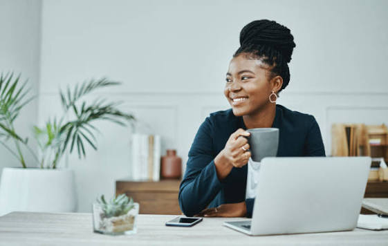 Realistic portrait of a young South African entrepreneur working confidently on a laptop in a modern small business workspace.