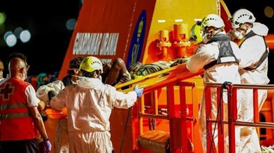 Rescue workers assist migrants from a boat near the Canary Islands